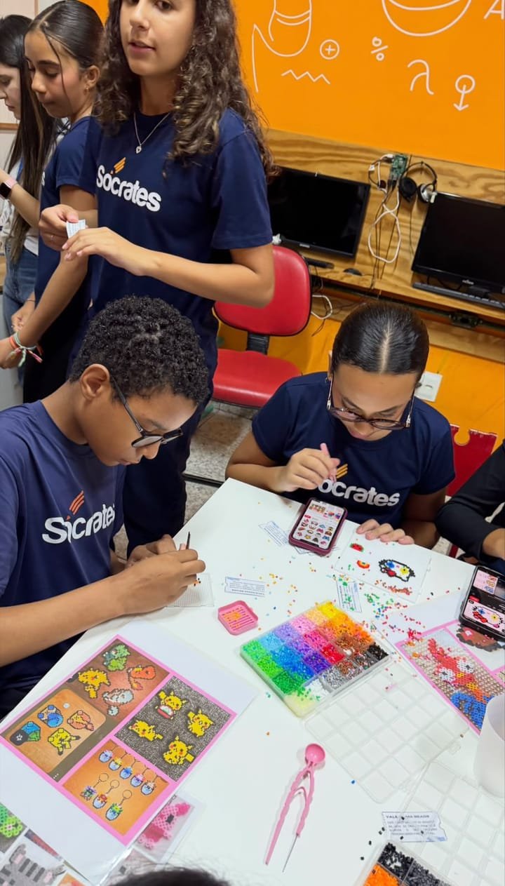 Alunos montando peças com miçangas coloridas sobre a mesa
