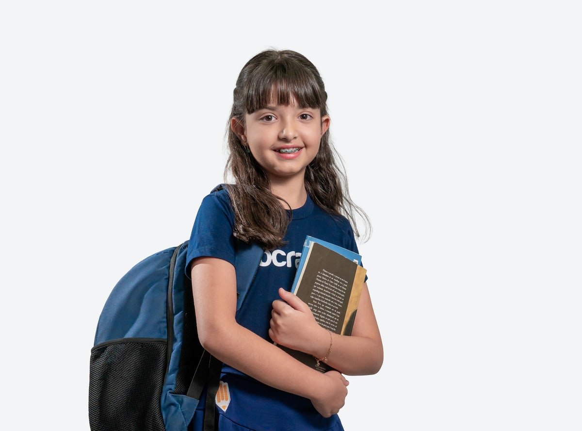 Aluna do Fundamental I do Colégio Sócrates com mochila nas costas, segurando seus livros